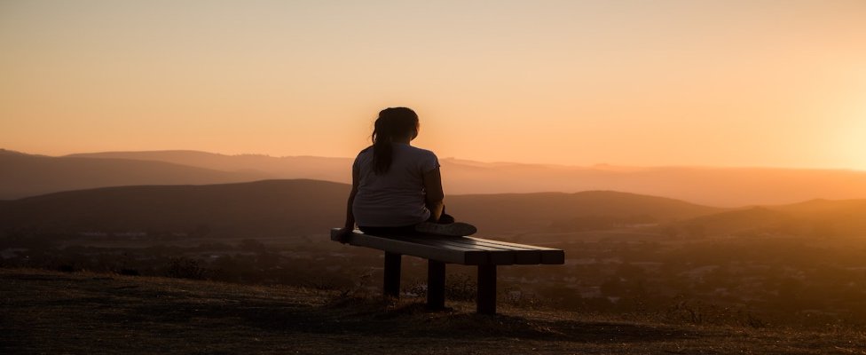 Picture of woman gazing into the sunset sitting on bench