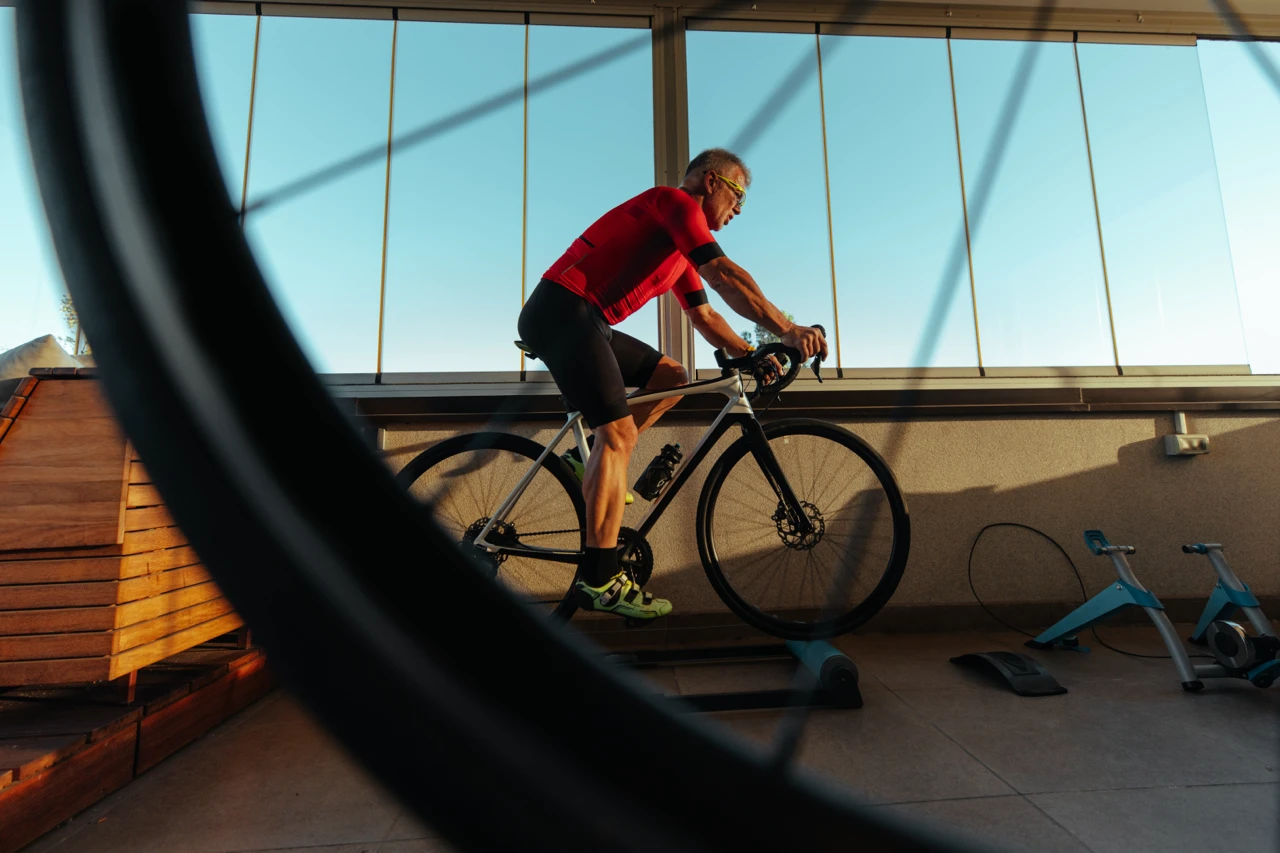 Cycliste qui s’entraîne sur une base d’entraînement devant une grande fenêtre.
