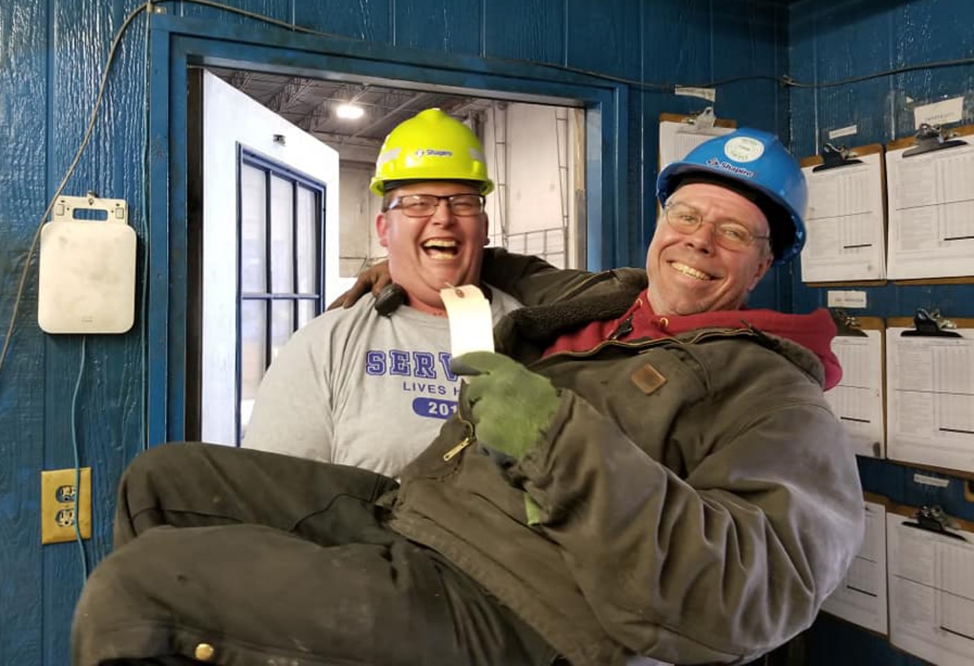 Two men in hard hats with one holding the other