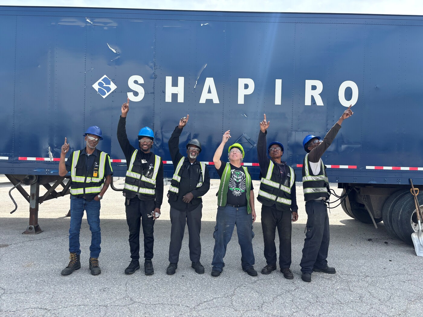 Shapiro team pointing up at their logo on their truck bed