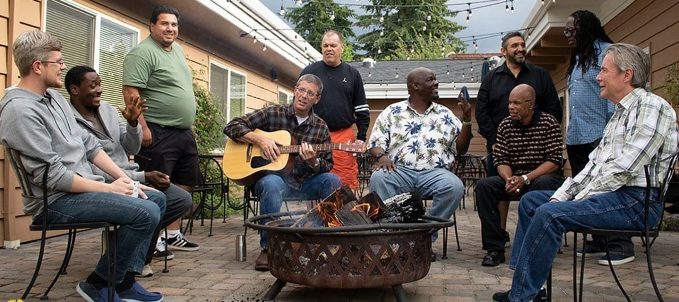  Men enjoying each others company sitting around a fire pit 