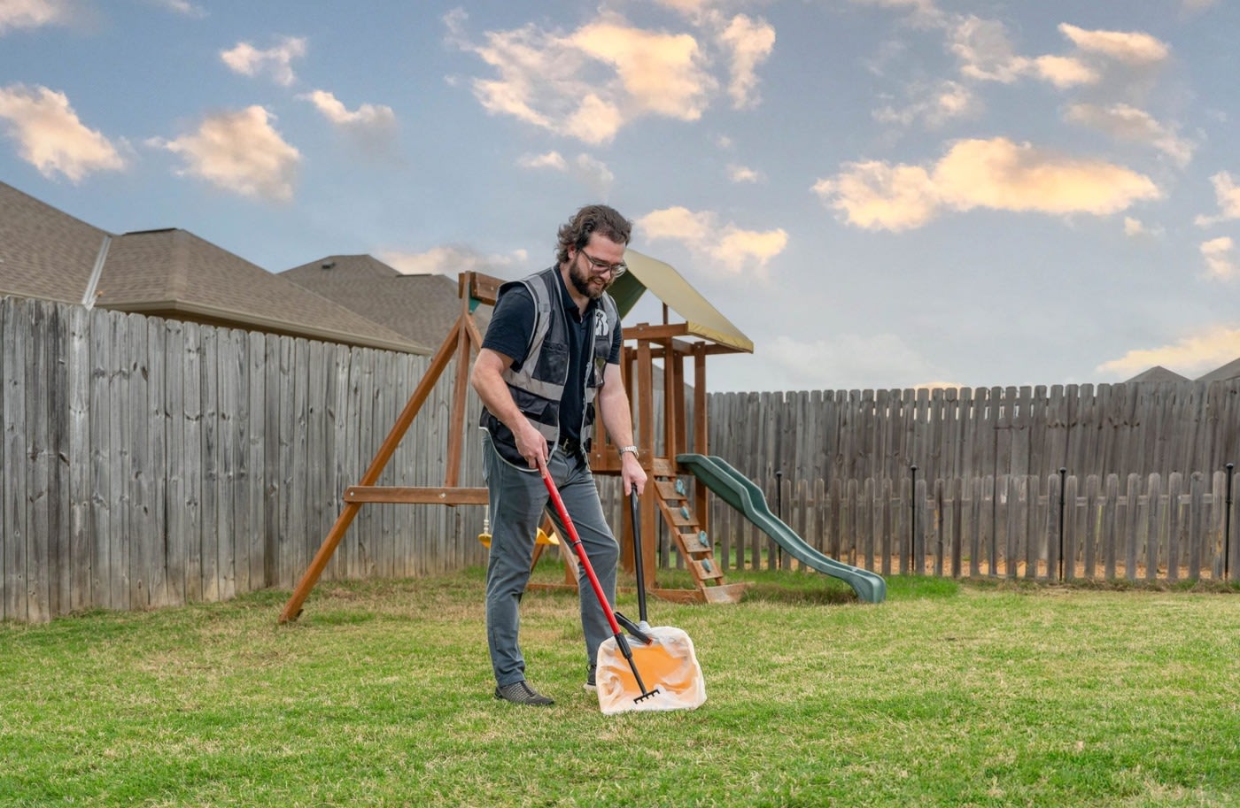Man scoopping dog poop in a backyard