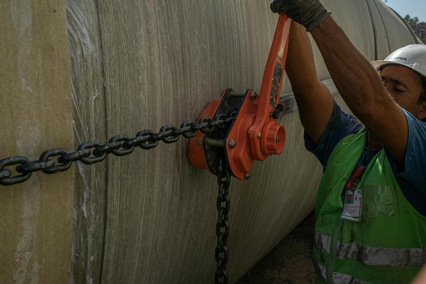 Worker adjusting a chain on a pipeline