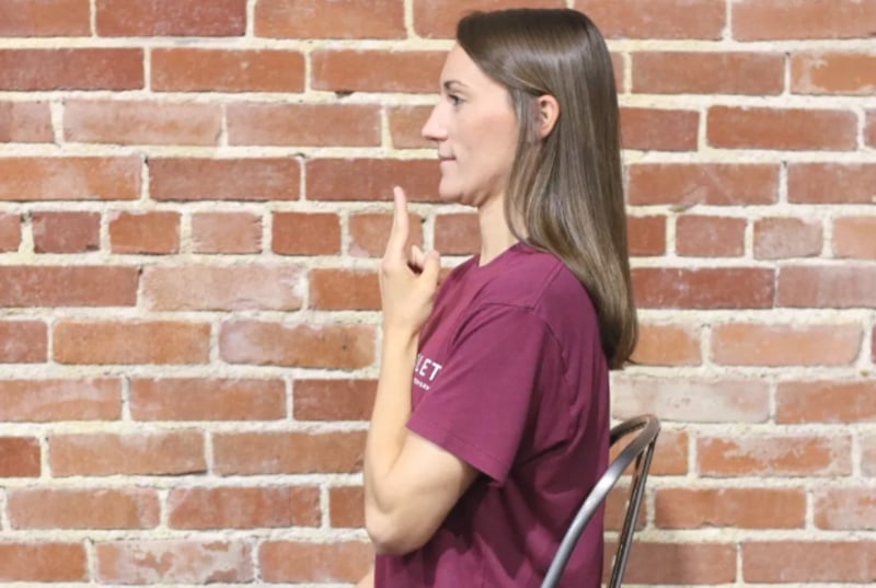 Woman holding her two fingers in front of her chin