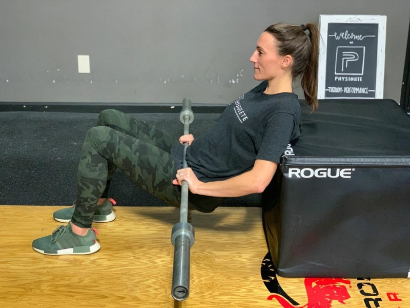 Barbell Hip Thrust, woman holding weight, both feet on ground, back against flat surface