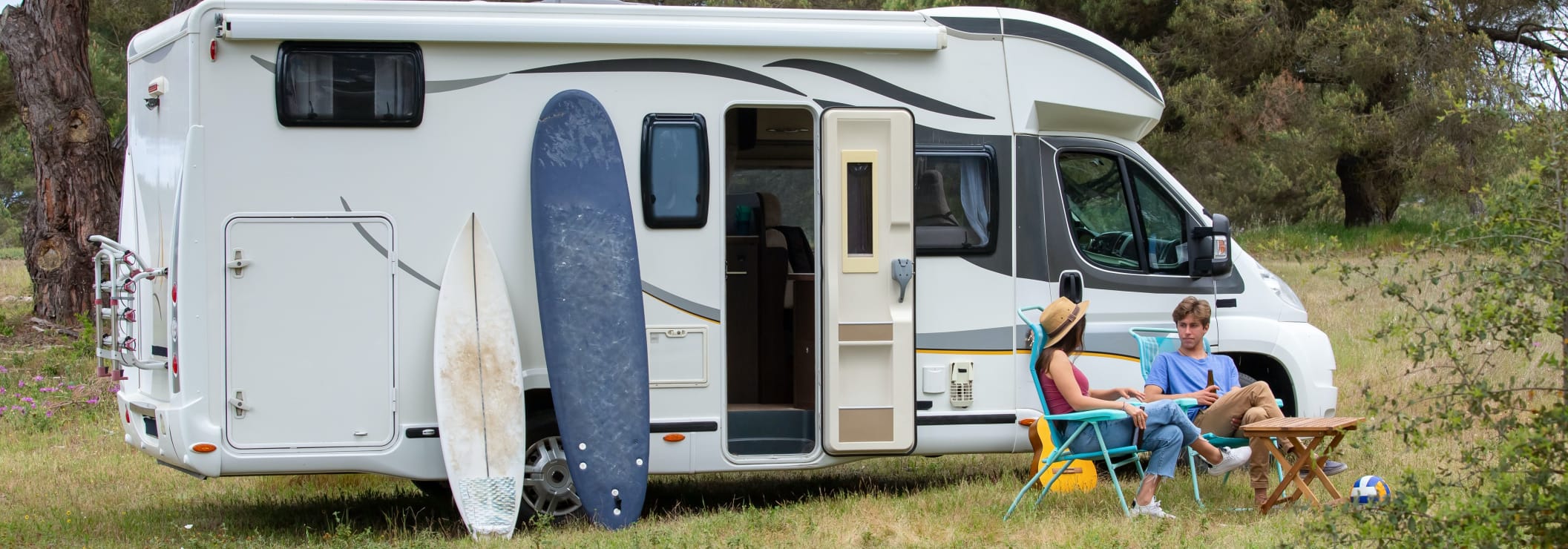 Wohnmobil mit Campingstühlen und Campern davor