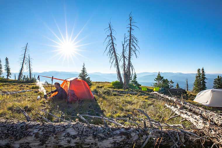 Camper cooking a meal under the awning-style vestibule of the Big Agnes Copper Spur HV UL2 Tent