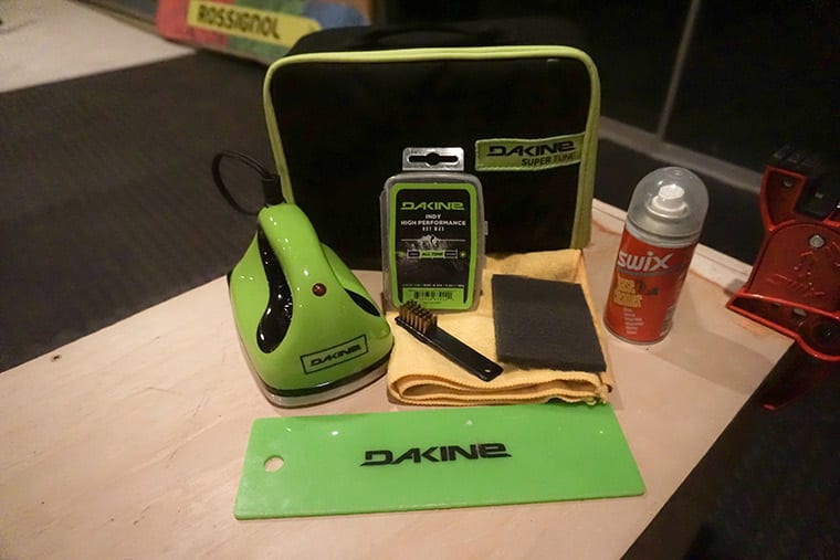 A Dakine waxing iron, scraper, base brush, wax, and Swix base cleaner