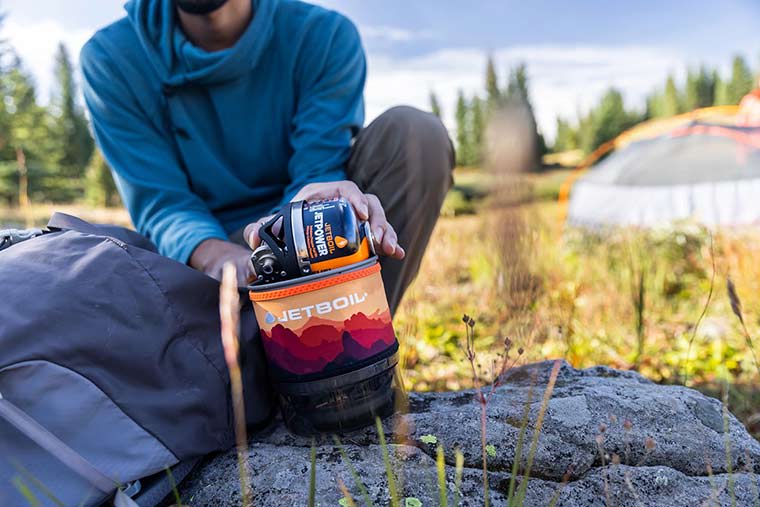 Camper packing the fuel regulator and 100g JetPower fuel into the Jetboil MiniMo cooking cup