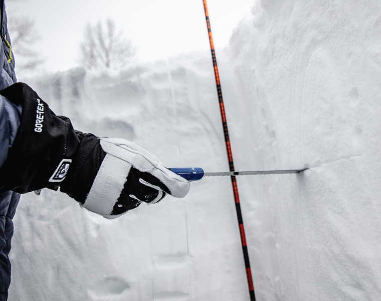 Using a snow saw to examine the snow pack in a snow pit