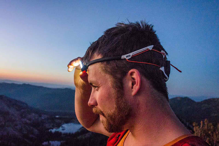 A man turning on the IKO CORE headlamp as the sun sets