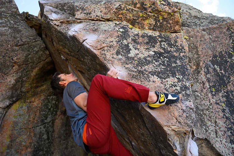 A climber bouldering outside while wearing the La Sportiva Solution climbing shoe