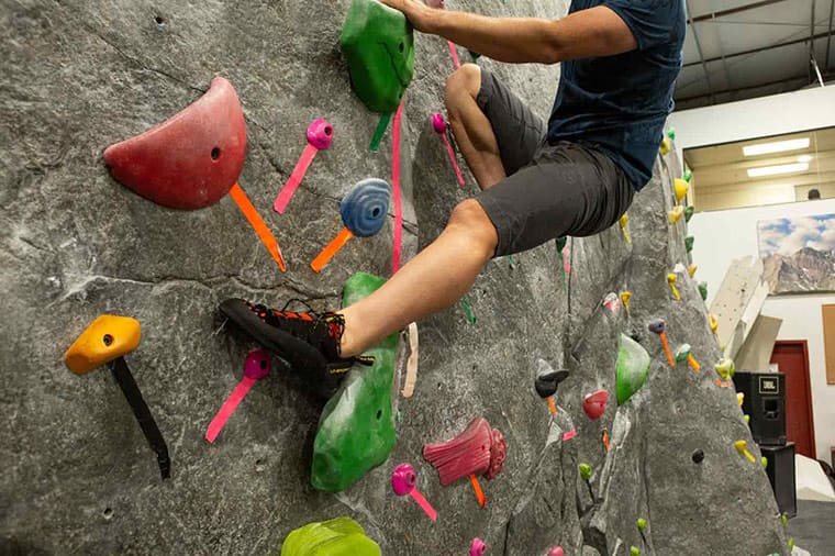 A climber in the gym heel hooking while wearing the La Sportiva Tarantulace climbing shoe