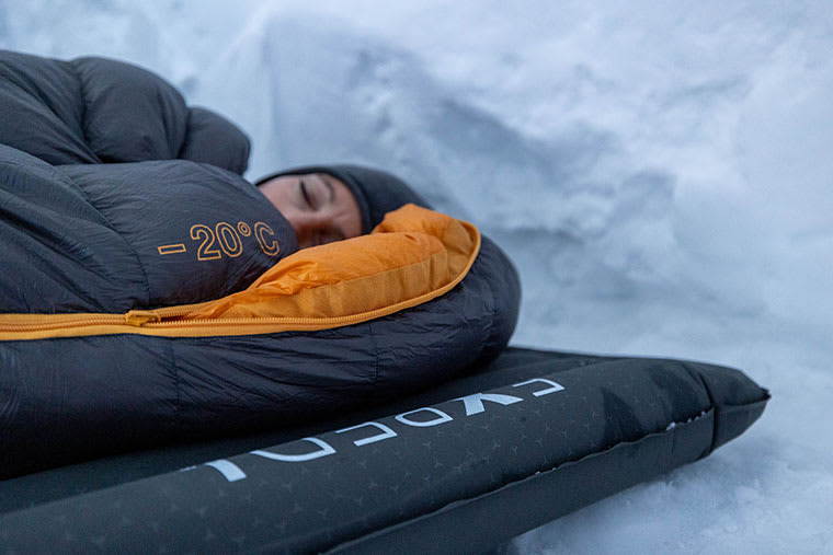 Camper inside of their sleeping bag on the Exped Versa Sleeping Pad in a snow cave