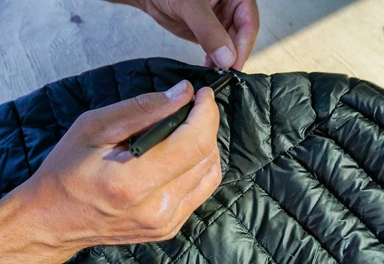 Using a pen to push down insulation back into a hole in the jacket.