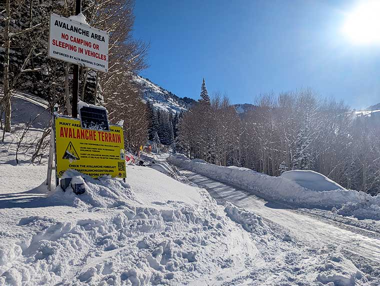 Snowy background with an Avalanche Terrain Sign at the entrance to Grizzly Gulch