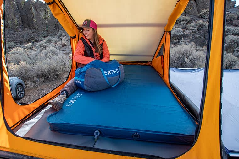 Camper sitting on the Exped DeepSleep Mat Duo 7.5 inside of their tent