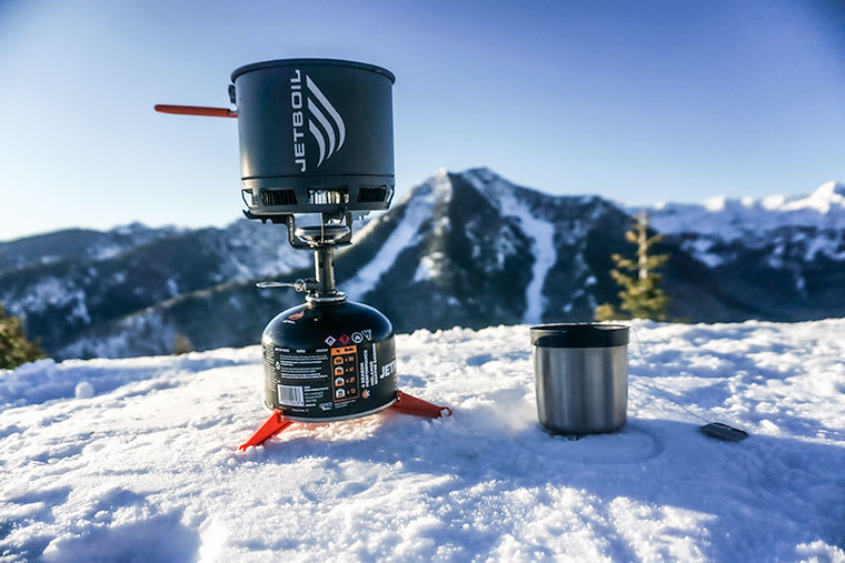 The Jetboil Stash next to a cup of tea on a mountaintop