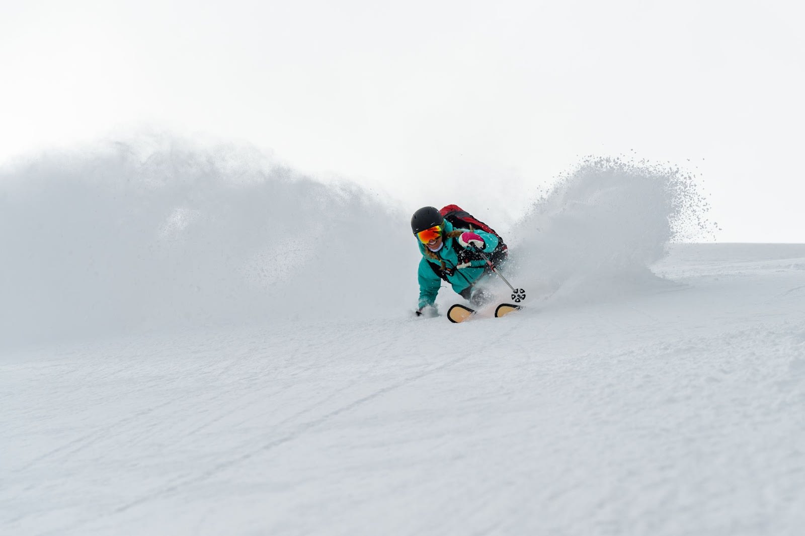 Skier in a green jacket skiing through powdery snow