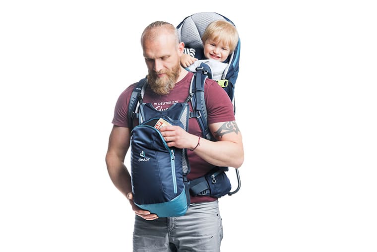 Man carrying child in the Deuter Kid Comfort Pro while checking out the included accessory pack