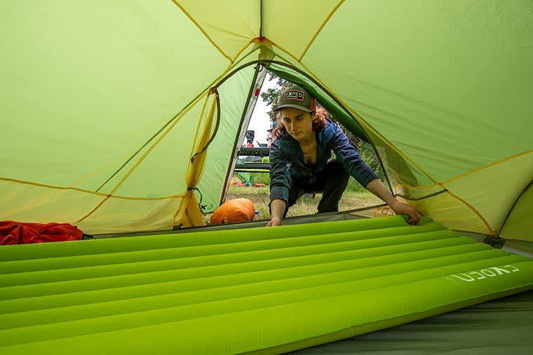 Camper placing an inflated Exped Ultra 3R Sleeping Pad inside of a tent