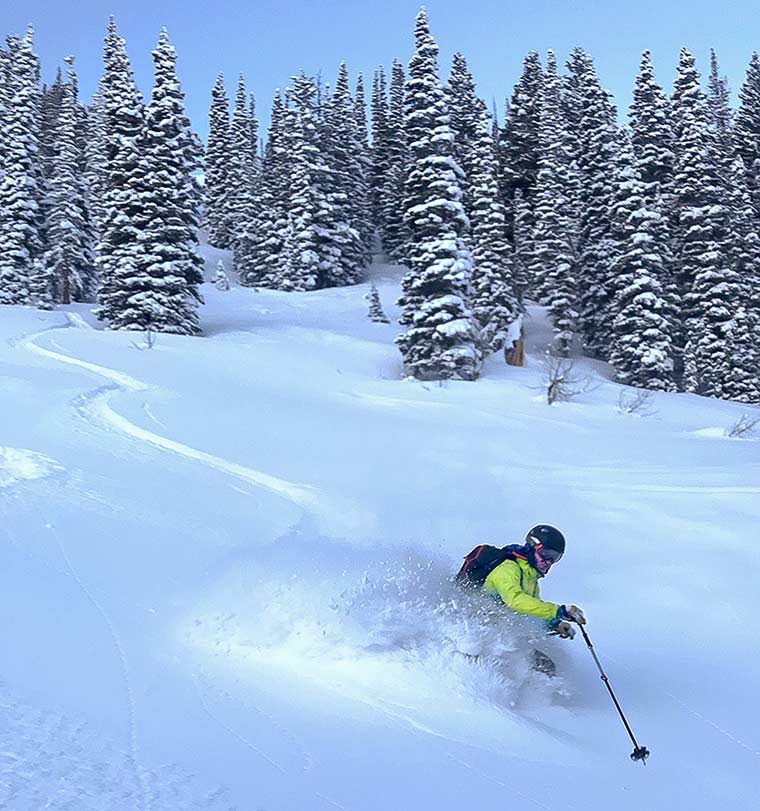 Skier at the end of a backcountry ski run spraying fresh powder