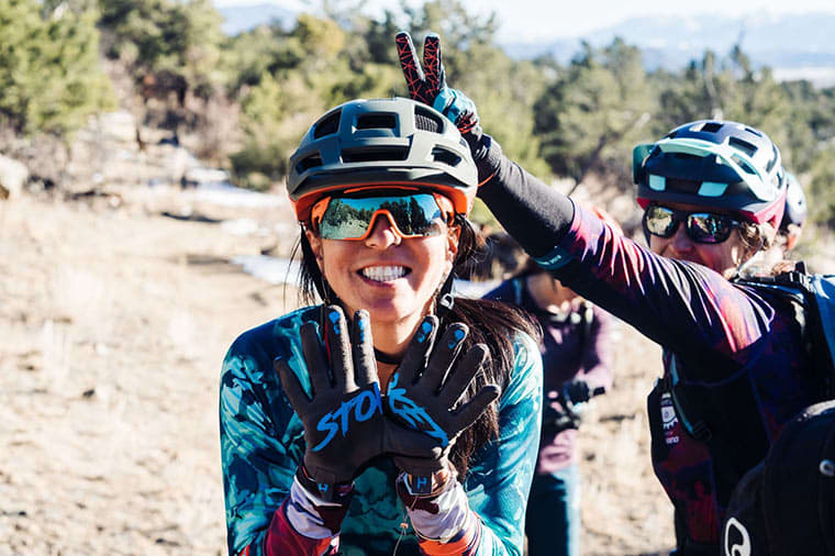 woman smiles at the camera while another woman makes the bunny ears hand signal behind her head