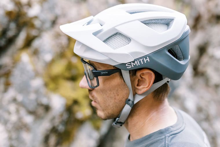 man stands next to a trail wearing a smith session helmet