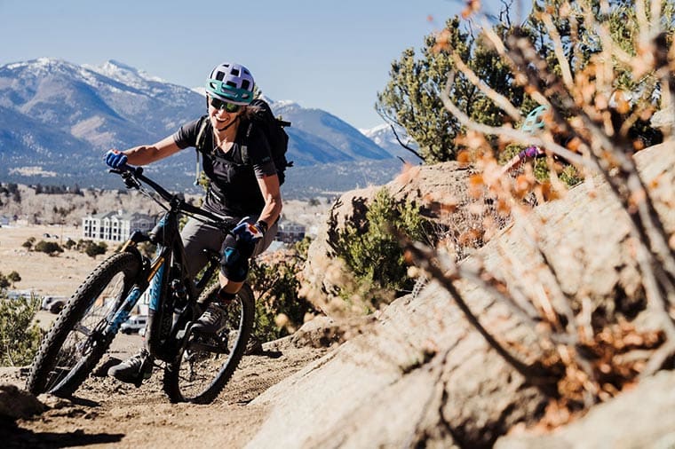 woman rounds a corner on a mountain bike with a smile on her face