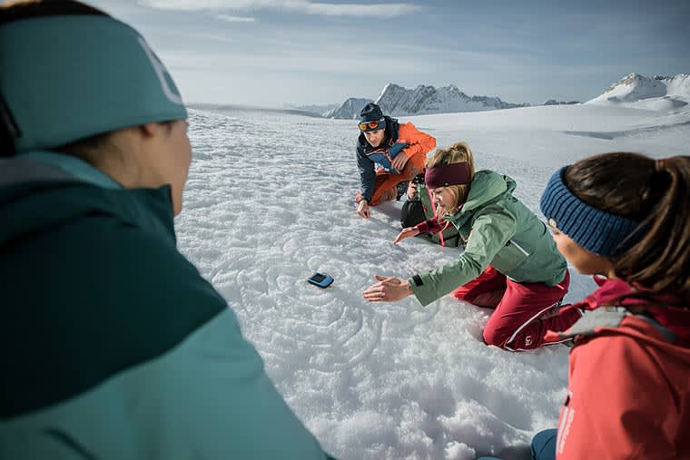 Avalanche instructor showing an avalanche safety class how beacons work 