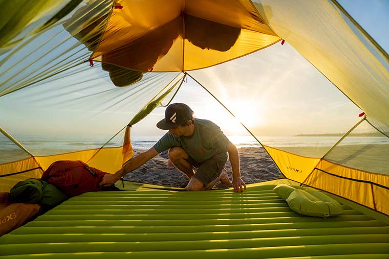 Camper inflating the Exped Ultra Duo 3R sleeping Pad inside of a tent