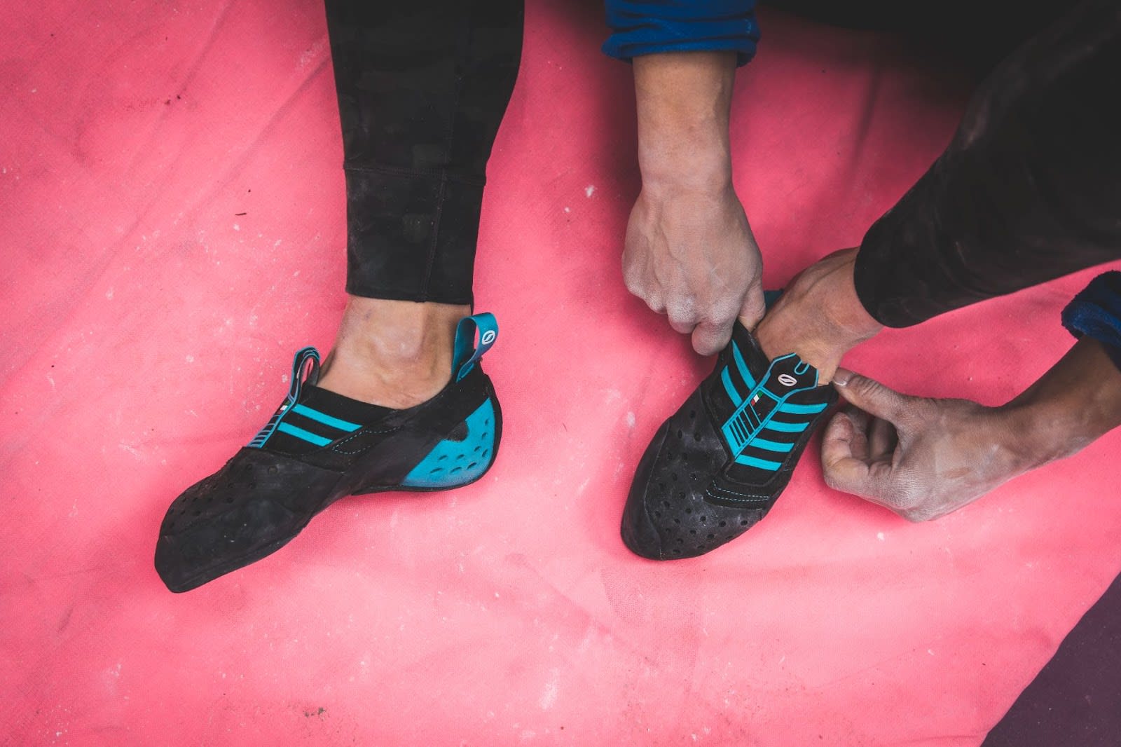 A climber sitting while pulling on the SCARPA Instinct S climbing shoe