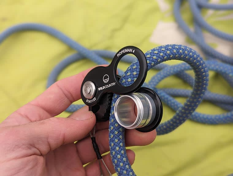 Hand holding a black Ropeman 4 on a blue climbing rope.