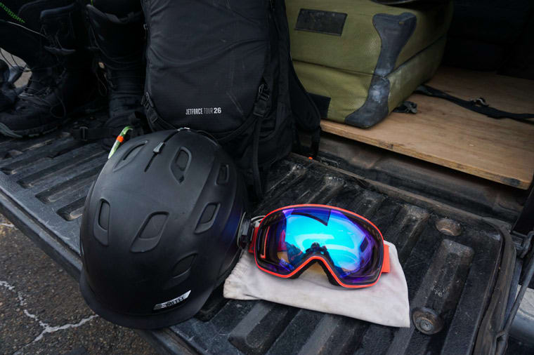 A ski helmet sits next to goggles on a tailgate