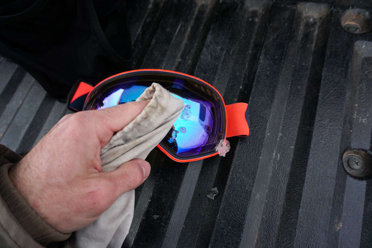 using a goggle bag to remove snow from ski goggles