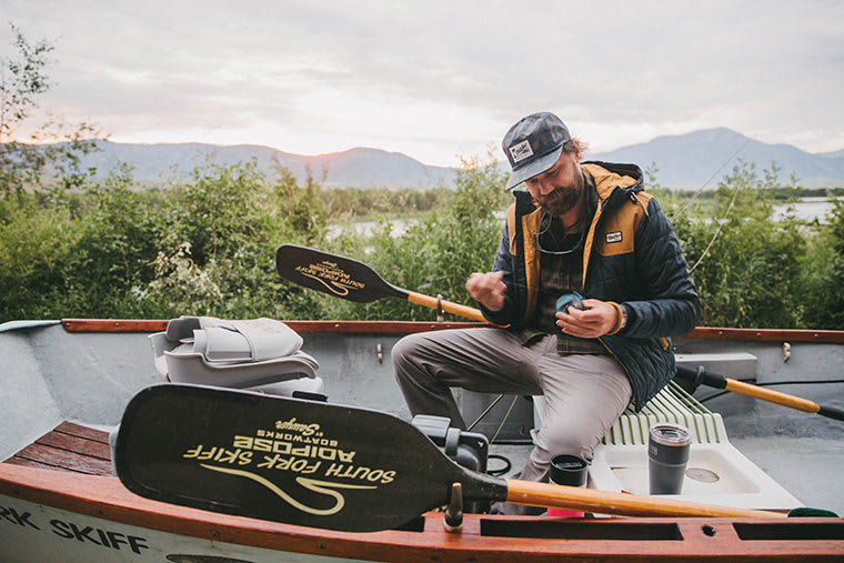 Fisherman sitting in a boat wearing the Howler Bros Spellbinder Parka