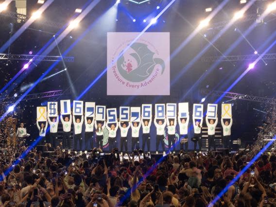 Students raise up cards with numbers reading "$16,955,683.63", the total funds raised during THON.