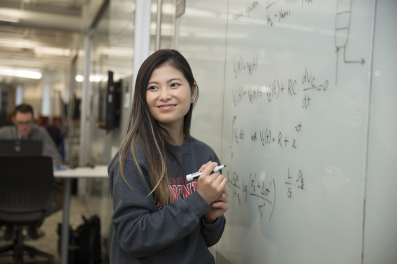 A student writes on a whiteboard