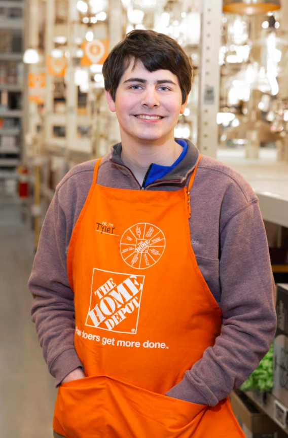 A man smiles for the camera while wearing an orange Home Depot apron