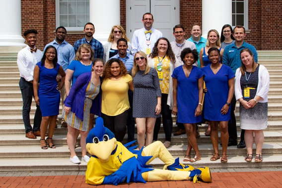 RLH  staff stand on the steps of Memorial Hall, UD's mascot, YoUDee, lays on the ground at their feet