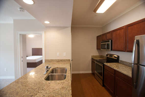 Interior of WKU apartment. Looking into the kitchen with the bedroom in the background. Granite countertops and stainless steel appliances.