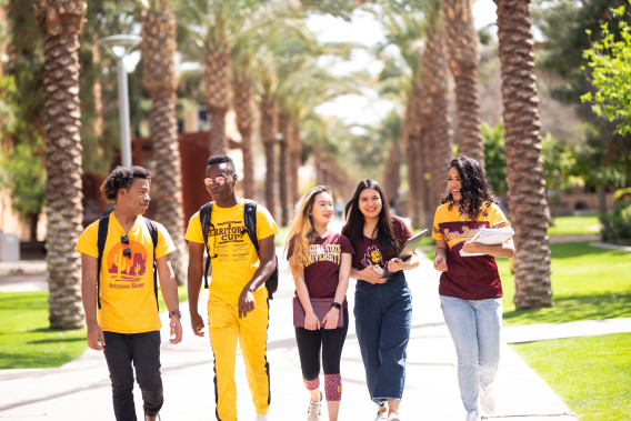 Students dressed in ASU clothing walking in a line down Palm Walk on the Tempe campus