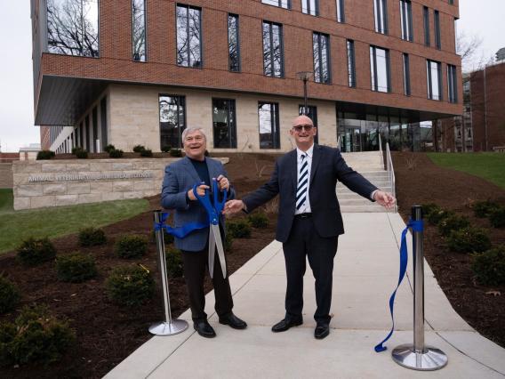 Two people cutting a giant ribbon