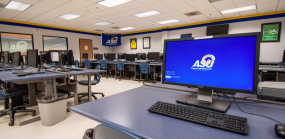 A computer with a blue background and ASU written in white on it sits amongst a group of other blank computers in a tiled room.