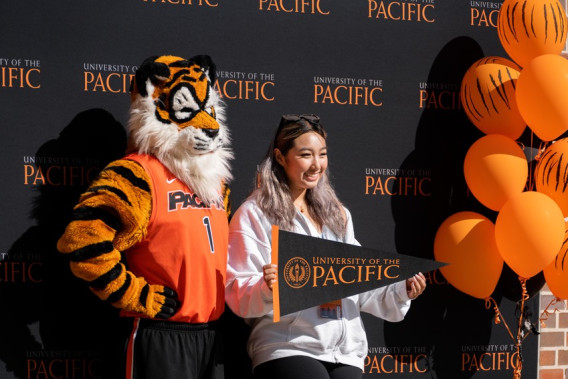 An admitted college student posing for a photo with University of the Pacific mascot, Power Cat.