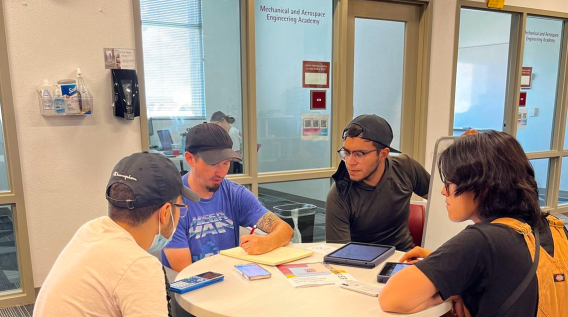 A group of people sit at a table and talk to each other