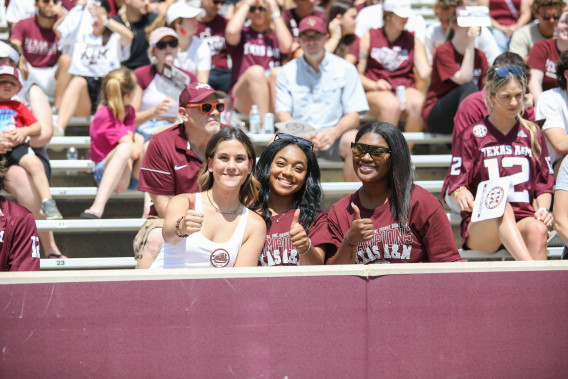 a group of student giving a thumbs up or "Gig'em" to the camera at a Texas A&M Football game 