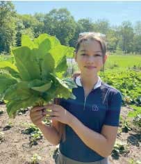 Zoe holding a lettuce in an indigenous food forest