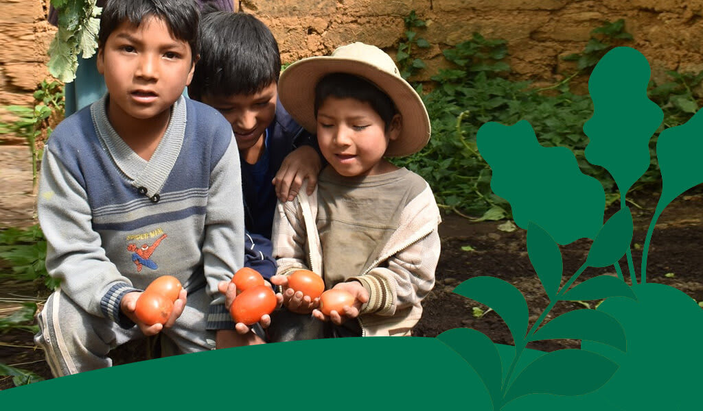 Bolivian children hold tomatoes from their veggie garden