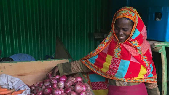 women standing in front of her produce for sale